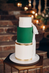 Three-tiered white and green wedding cake with gold accents