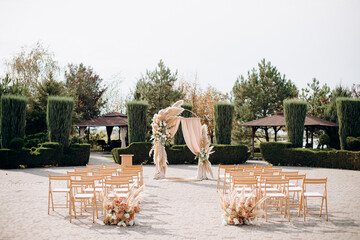 A grand ceremony in a spacious courtyard surrounded by trimmed bushes and trees, with a pampas...