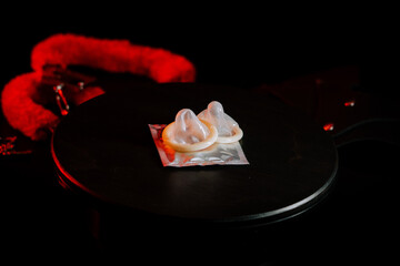 Condoms placed on a black surface with playful accessories and dramatic lighting effects