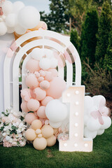 Outdoor birthday photo zone with white arch, pink balloons, and neon Happy Birthday sign