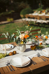 Outdoor table setting with floral arrangements and candles. Warm, summer atmosphere