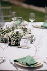 Elegant table setting with white flowers and number four. Bright, outdoor atmosphere