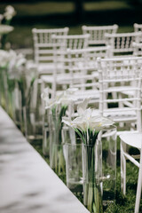 Elegant outdoor wedding aisle with white calla lilies in glass vases