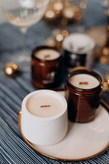 A collection of candles in white gypsum and brown glass jars with wooden wicks. Cozy and elegant home decor, perfect for relaxation and a warm ambiance