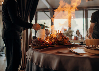 Chef flambéing a platter of meat with a gas torch at a station
