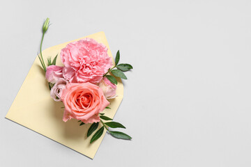 Composition with envelope and beautiful flowers on grey background