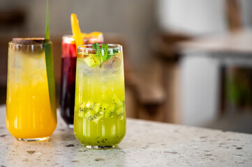 Refreshing cocktails in vibrant glasses, featuring bright colors. Slices of kiwi and garnishes enhance the tropical appeal, perfect for summer gatherings or celebrations.