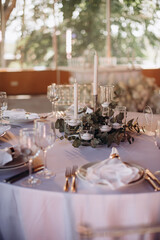 Many thin white candles in slender single candle holders burning on a banquet table in a restaurant, featuring pastel tones and a chic, minimalist atmosphere for a celebration or banquet