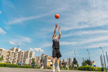 Passionate Basketball Player Shooting Hoops in a Vibrant Urban Court Under a Clear Blue Sky