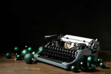 Vintage typewriter with Christmas balls on wooden table