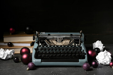 Vintage typewriter with Christmas balls and books on black background