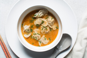 Overhead view of curry wonton soup in a white ceramic bowl, red curry soup with dumplings in a white soup bowl