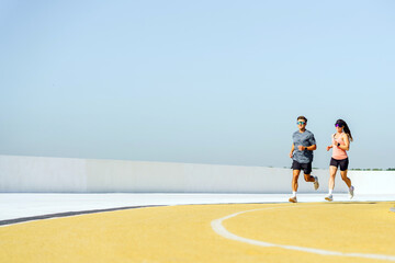 Two Friends Enjoy an Energetic Morning Run on a Rooftop Track Under a Clear Blue Sky