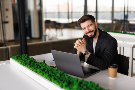 Mmm...I wonder. Handsome young businessman looking thoughtful while working on his laptop in the office.