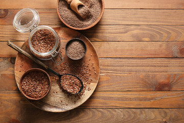 Jar with flax seeds and bowls of flour on wooden background