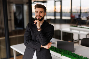 Thoughtful doubtful company ceo executive standing in office holding hand in chin looking at camera...