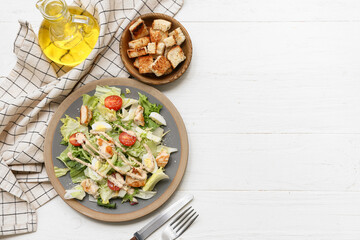 Plate with tasty chicken Caesar salad and bowl of croutons on white wooden background