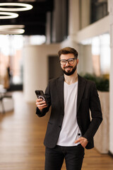 Successful financier man smiles and reads good news online from smartphone.