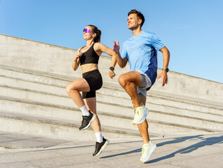 Energetic Joggers Practicing on Modern Urban Steps Under a Bright Blue Sky at Sunset