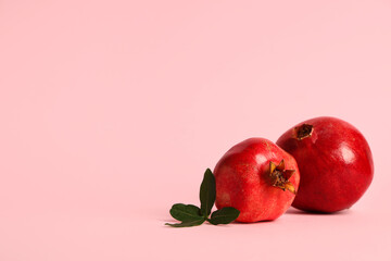 Fresh ripe pomegranates and leaves on pink background