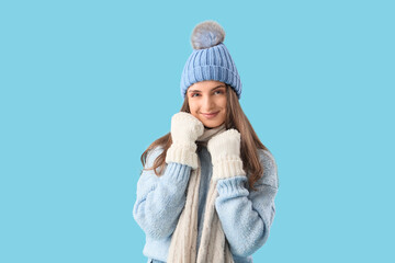 Beautiful young woman in stylish warm clothes on blue background