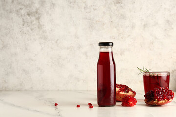 Bottle and glass of fresh pomegranate juice with rosemary on white background