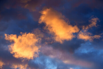 Glowing orange clouds illuminate a deep blue sky during a dramatic sunset.
