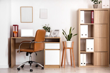 Interior of light office with workplace, shelf unit and blank frames