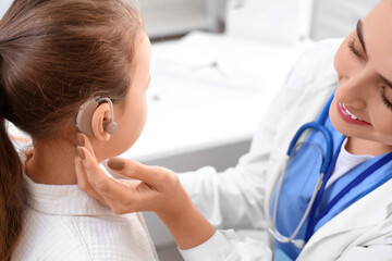 Little girl with hearing aid and doctor in clinic, closeup