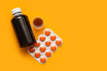 Bottle and measuring cup of cough syrup with pills for sore throat on orange background