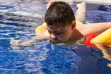 Child with cerebral palsy swimming with floatation device in pool