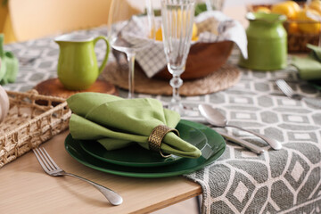 Stylish green table setting decorated with fresh lemons in dining room