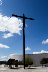 Tall minimalist cross sculpture in a sunny Fatima, Portugal landscape