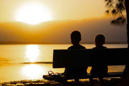 Two young boys at sunset on a park bench