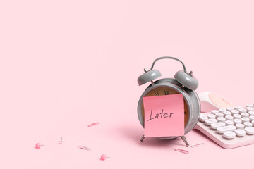 Sticky note with word LATER, alarm clock, computer keyboard and mouse on pink background