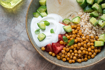 Closeup of a chickpea bowl with greek yogurt, fresh vegetables and brown rice, horizontal shot, selective focus