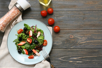 Plate of salad with crab sticks, spinach, black olives and tomatoes on wooden background © Pixel-Shot