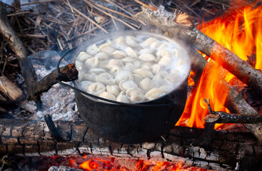 dumplings are boiled in a pot over a fire