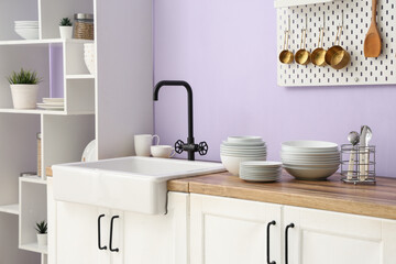 Clean plates and bowls near sink in stylish kitchen, closeup