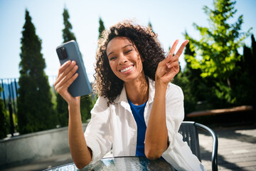 Cheerful young woman enjoying a sunny day taking a selfie outdoors in the city