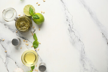 Jar of delicious pesto sauce with ingredients on marble background
