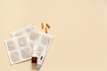 Mustard plasters with pills, nasal drops and thermometer on beige background