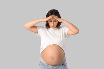Pregnant woman suffering from toxicosis on  grey background