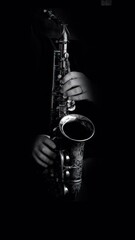 Fototapeta premium close up of saxophone player hands performing jazz music on vintage engraved saxophone in dark background..