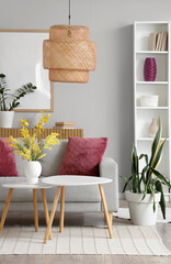 Interior of modern living room with shelving unit, coffee tables and purple pillows on sofa