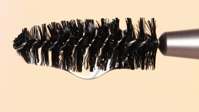 Macro brush for eyebrows and eyelashes on beige background with cosmetic hair oil.