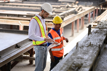 Engininspecting the work that technicians are doing by pouring cement for building components and...