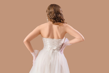 Beautiful bride in white wedding dress on beige background, back view