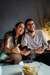 Young caucasian couple smile and play video games on joystick	
