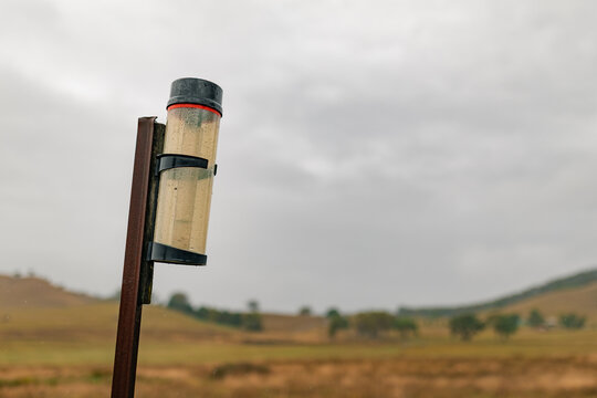 Rain gauge on rural farm property measuring rainfall on stormy day